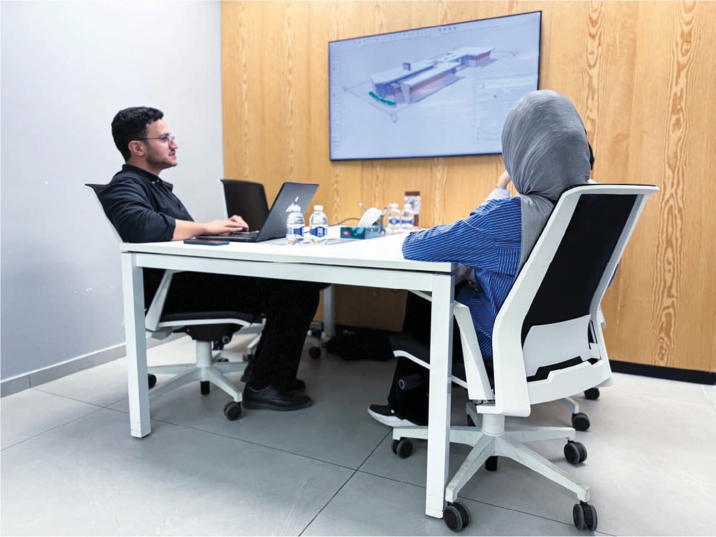 Welcome Room - two people working with laptops and 3D model on TV