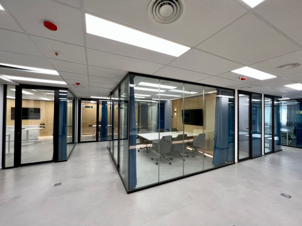 Modern glass-walled meeting rooms with blue curtains